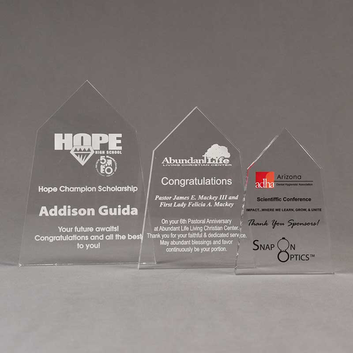 Three crystal clear acrylic obelisk shaped acrylic trophies with laser engraved recognition text.